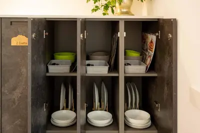 a cabinet with plates and utensils in it at La Corte Delle Dolomiti in Agordo