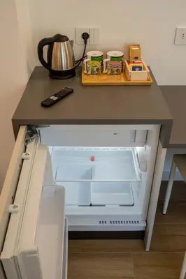 a kitchen counter with an open refrigerator and a tea kettle at La Corte Delle Dolomiti in Agordo
