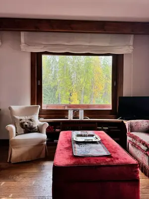 a living room with a window and a table and a chair at Via Cantore Exclusive Stay in Cortina dʼAmpezzo
