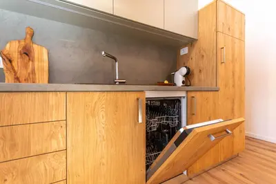 a kitchen with wooden cabinets and a dishwasher at Hapina Dolomiti with Garage in Cencenighe