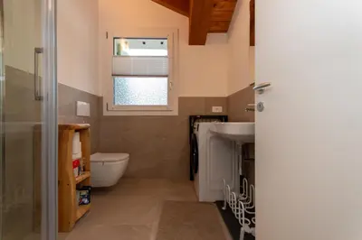 a bathroom with a sink and a toilet and a window at Hapina Dolomiti with Garage in Cencenighe
