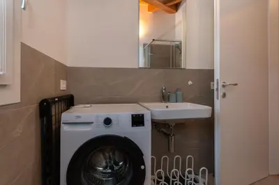 a bathroom with a washing machine and a sink at Hapina Dolomiti with Garage in Cencenighe