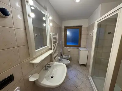 a bathroom with two sinks and a shower and a toilet at Appartamento Fontane in Panchia