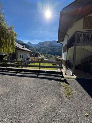a fence next to a house with mountains in the background at Appartamento Fontane in Panchia