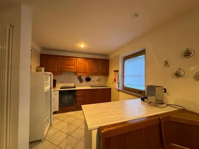 a kitchen with wooden cabinets and a white refrigerator at Appartamento Fontane in Panchia
