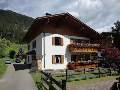 a white house with flowers on the balcony at Appartamento Ciamp in Pozza di Fassa
