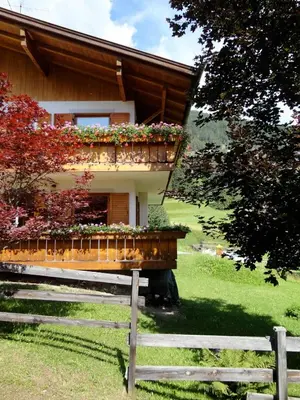 a house with a balcony with flowers on it at Appartamento Ciamp in Pozza di Fassa