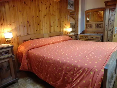 a bedroom with a bed in a room with wooden walls at Appartamento Ciamp in Pozza di Fassa