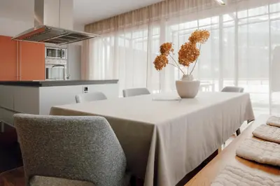 a dining room with a table with chairs and a vase with flowers at Kronsun Percha in Perca
