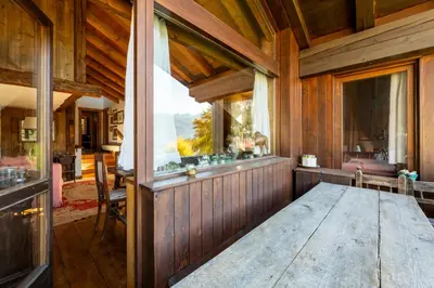 a dining room with a table and a large window at Villa Allegra 2 Tofane monuntains view in Cortina dʼAmpezzo