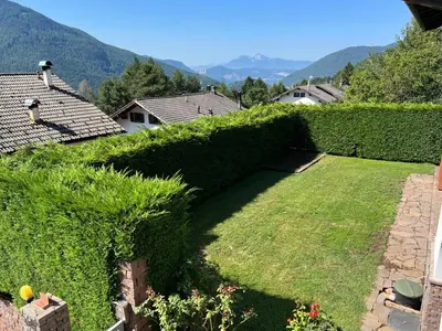 a garden with a hedge and a lawn with mountains in the background at Villa Grumes by Sunhome Fiemme in Grumes