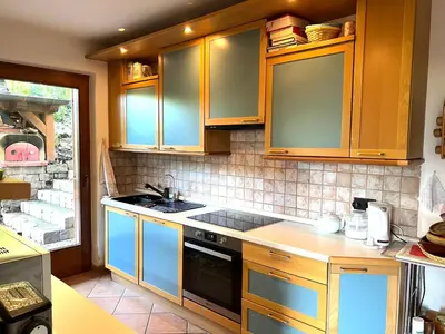 a kitchen with wooden cabinets and a stove top oven at Villa Grumes by Sunhome Fiemme in Grumes