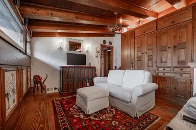 a living room with a white couch and a tv at GuestHost - Cortina Charming Wooden Alpine Nest in Cortina dʼAmpezzo