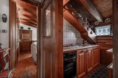 a kitchen with wooden cabinets and a stove top oven at GuestHost - Cortina Charming Wooden Alpine Nest in Cortina dʼAmpezzo