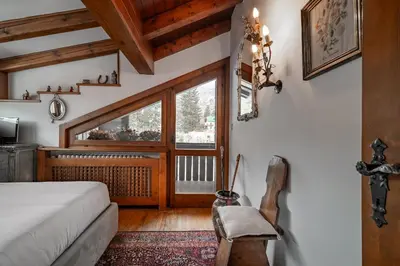 a bedroom with a bed and a window at GuestHost - Cortina Charming Wooden Alpine Nest in Cortina dʼAmpezzo
