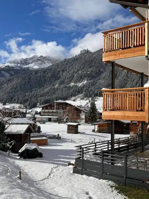 a ski lodge with a snow covered mountain in the background at Cesa Bernard - Apartment Cima 12 e new Apartment Fraine in Pozza di Fassa