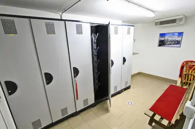 a row of lockers in a room with a red chair at Cesa Bernard - Apartment Cima 12 e new Apartment Fraine in Pozza di Fassa