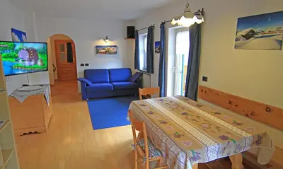 a living room with a blue couch and a tv at Cesa Bernard - Apartment Cima 12 e new Apartment Fraine in Pozza di Fassa