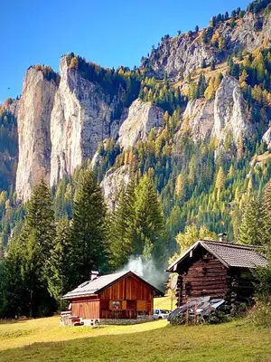 a barn in a field with a mountain in the background at Cesa Bernard - Apartment Cima 12 e new Apartment Fraine in Pozza di Fassa