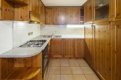 a kitchen with wooden cabinets and a stove top oven at Villa Lacedel - Stayincortina in Cortina dʼAmpezzo