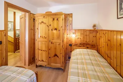 a bedroom with a bed and a wooden wall at CiasaToa in Cortina dʼAmpezzo