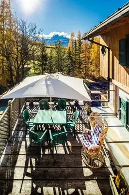 a patio with a table and chairs and an umbrella at CiasaToa in Cortina dʼAmpezzo