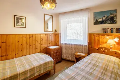 a bedroom with two beds and a window at CiasaToa in Cortina dʼAmpezzo