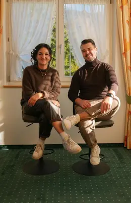 a man and a woman sitting on chairs in front of a window at Hotel Roduna in Rodengo