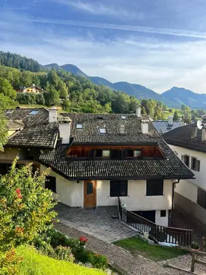 a house with a roof with mountains in the background at Casa Vacanze Carano - El Me Tabià in Carano