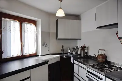 a kitchen with white cabinets and a sink and a stove at Casa Vacanze Carano - El Me Tabià in Carano