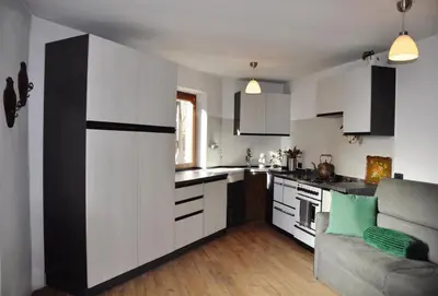 a kitchen with white cabinets and a couch at Casa Vacanze Carano - El Me Tabià in Carano