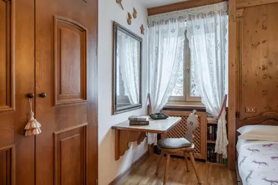 a bedroom with a desk and a bed and a window at Apartment Tiarè by My Villa Collection in Cortina dʼAmpezzo