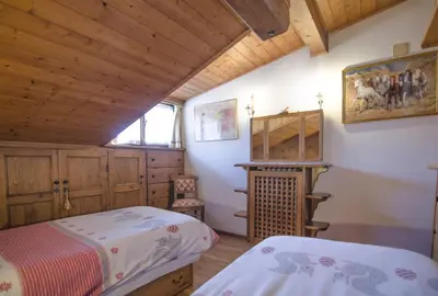 a bedroom with two beds in a room with wooden ceilings at La tua mansada in montagna - Comfort e vista in Cortina dʼAmpezzo