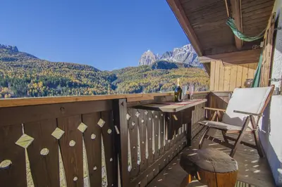 a chair on a balcony with a view of mountains at La tua mansada in montagna - Comfort e vista in Cortina dʼAmpezzo