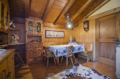 a kitchen with a table and chairs and wooden walls at La tua mansada in montagna - Comfort e vista in Cortina dʼAmpezzo