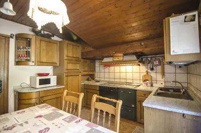 a kitchen with wooden cabinets and a table with chairs at La tua mansada in montagna - Comfort e vista in Cortina dʼAmpezzo