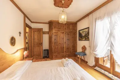 a bedroom with a white bed and a window at Casa La Marignana, ricca di comfort a Cortina d Ampezzo in Cortina dʼAmpezzo