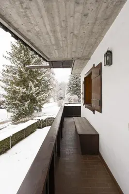 a balcony with a wooden bench and a window at Casa La Marignana, ricca di comfort a Cortina d Ampezzo in Cortina dʼAmpezzo