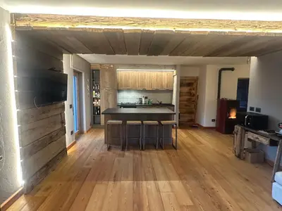 a kitchen and living room with a wooden floor at Appartamento PELMO in Selva di Cadore