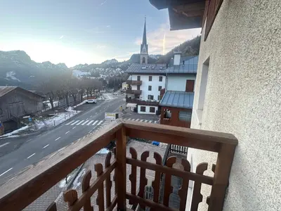 a balcony with a view of a street and a church at Appartamento PELMO in Selva di Cadore