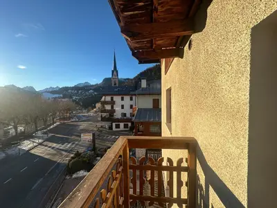 a balcony with a view of a street and a church at Appartamento PELMO in Selva di Cadore