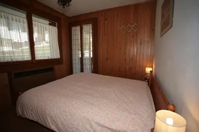 a bedroom with a bed and two windows at Appartamento Doleda in Canazei