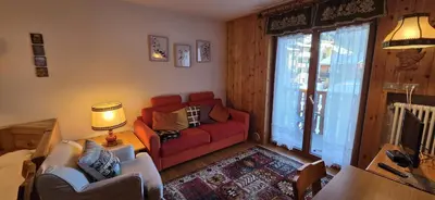 a living room with a red couch and a chair at Casa Vaiolet in Pozza di Fassa
