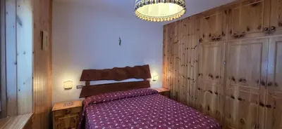 a bedroom with a bed and a chandelier at Casa Vaiolet in Pozza di Fassa