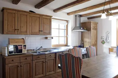 a kitchen with wooden cabinets and a wooden table at Maso Gretel in Tesero