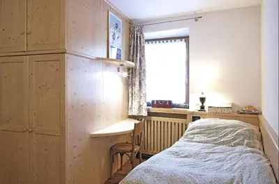 a bedroom with a bed and a desk and a window at Maso Gretel in Tesero