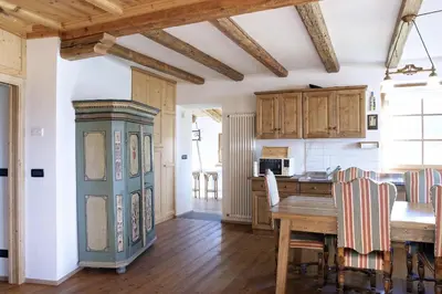 a kitchen with a wooden table and a dining room at Maso Gretel in Tesero