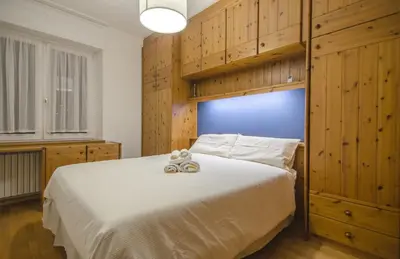 a bedroom with a large white bed with wooden cabinets at Nel cuore di Cortina comodo appartamento con parcheggio in Cortina dʼAmpezzo