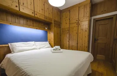 a bedroom with a large white bed with wooden cabinets at Nel cuore di Cortina comodo appartamento con parcheggio in Cortina dʼAmpezzo