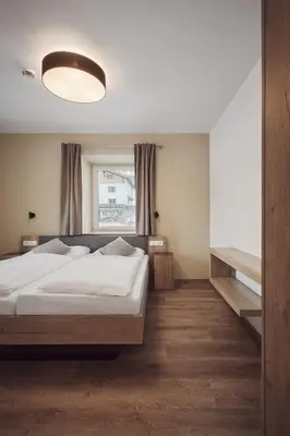 a bedroom with a large bed and a window at Apartments Knappenhof Pfitsch - with Swimming Pool in Val di Vizze